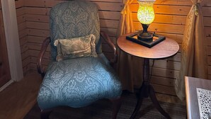 A wooden-paneled room with a patterned armchair, a small table with a mosaic lamp, and a mirror on the wall. - Paradise 2.0 at North River  (Beaufort)