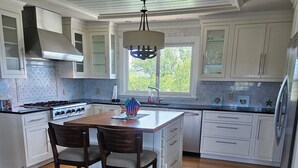 A modern kitchen with white cabinetry, a central island, a gas stove, and a large window providing natural light. - Paradise 2.0 at North River  (Beaufort)