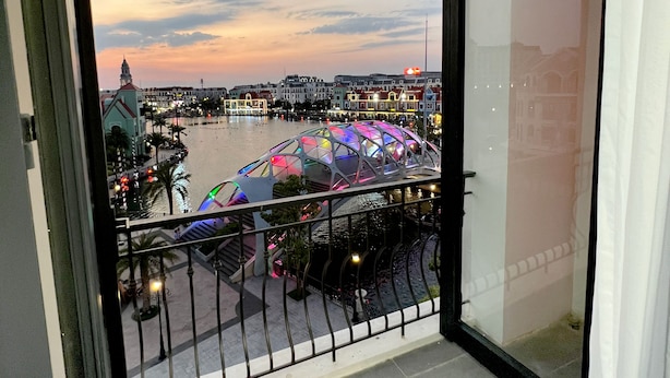 Een balkon met uitzicht op een waterkant, inclusief een kleurrijk gebouw en een brug.