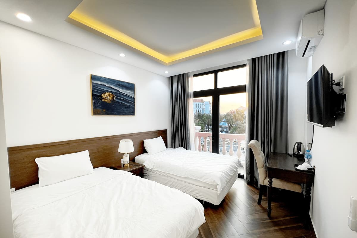 A hotel room with two beds, a desk, a TV, and a painting on the wall.