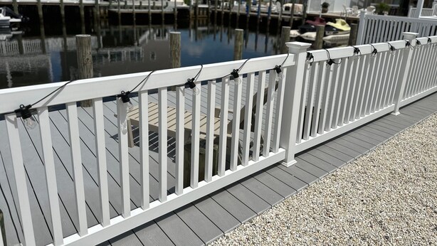 A waterfront property with a wooden deck, a white fence, and a calm water body. - Recently Renovated 3 Bedroom 1 Bath Clean Waterfront home with 50' Dock  (Stafford Township)