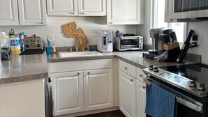 A kitchen with white cabinets, a microwave, a toaster, and a clock on the wall. - Recently Renovated 3 Bedroom 1 Bath Clean Waterfront home with 50' Dock  (Stafford Township)