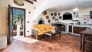 Un espacio de sala acogedor con sofá, mesa de centro y chimenea. Se ve una cocina con estufa y armarios al fondo.