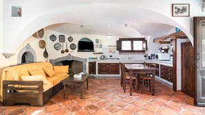Una cocina rústica con horno de piedra, mobiliario de madera y suelo de baldosas.