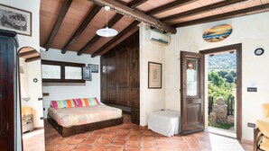 Un dormitorio con cama, una mesita, una puerta que da a un balcón y vistas al exterior.