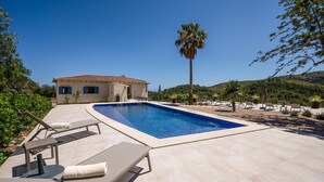 A swimming pool with lounge chairs, a palm tree, and a building with a tiled roof. - Beautiful home in Son Macia (Son Macia)