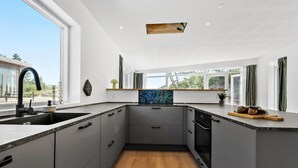A modern kitchen with grey cabinetry, a black faucet, and a wooden floor.