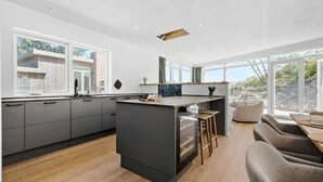 A modern kitchen with a central island, large windows, and a view of the outdoors.