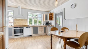 Een moderne keuken met houten kasten, een eettafel en een klok aan de muur.