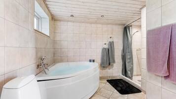 A bathroom with a bathtub, a toilet, and a shower area.