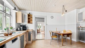 Een moderne keuken met houten kasten, een eettafel met stoelen en een uitzicht op een eetgedeelte.