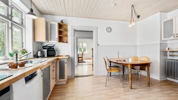 Une cuisine moderne avec des meubles en bois, une table à manger avec des chaises et une vue sur l’espace repas.