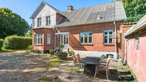 Een twee verdiepingen tellend huis van baksteen met een schuin dak, een veranda en een grindpad.