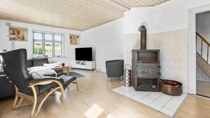Een moderne woonkamer met een open haard, een bank, een televisie en een eethoek.