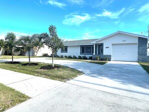 A single-story house with a garage, a driveway, and three palm trees in the front yard. - SAUNA! HUGE HOT TUB HEATED POOL UPDATED HOME 3 mileto beach 3BD 2BA 3 KING BEDS! (Seminole)