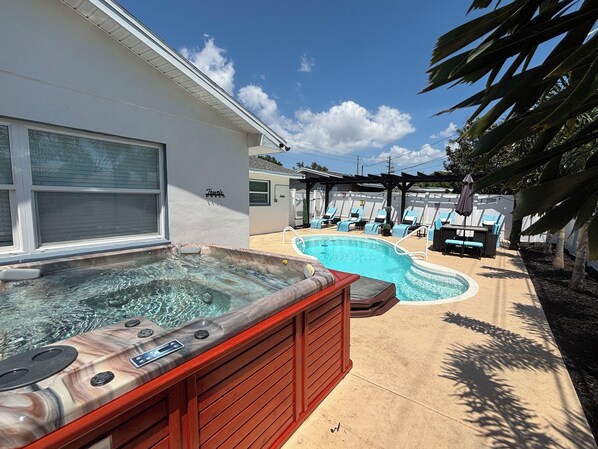 A hot tub and a swimming pool in a backyard with lounge chairs and a pergola. - SAUNA! HUGE HOT TUB HEATED POOL UPDATED HOME 3 mileto beach 3BD 2BA 3 KING BEDS! (Seminole)