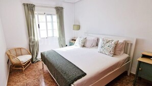 A bedroom with a bed, a chair, a nightstand, and a window with curtains. - Beautiful and Peacefull 3 Bed Villa with Private Pool, AC (Avileses)