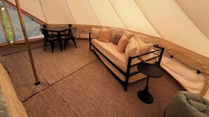 A tent with a sofa, a table, and chairs. - Meadow View Tent Glamping (Tetonia)