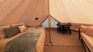 A tent with a bed, a table, and chairs. - Meadow View Tent Glamping (Tetonia)