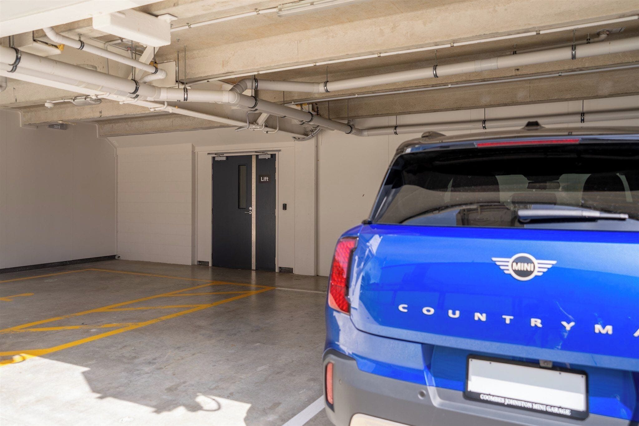 Un estacionamiento con un SUV azul aparcado en un espacio reservado.