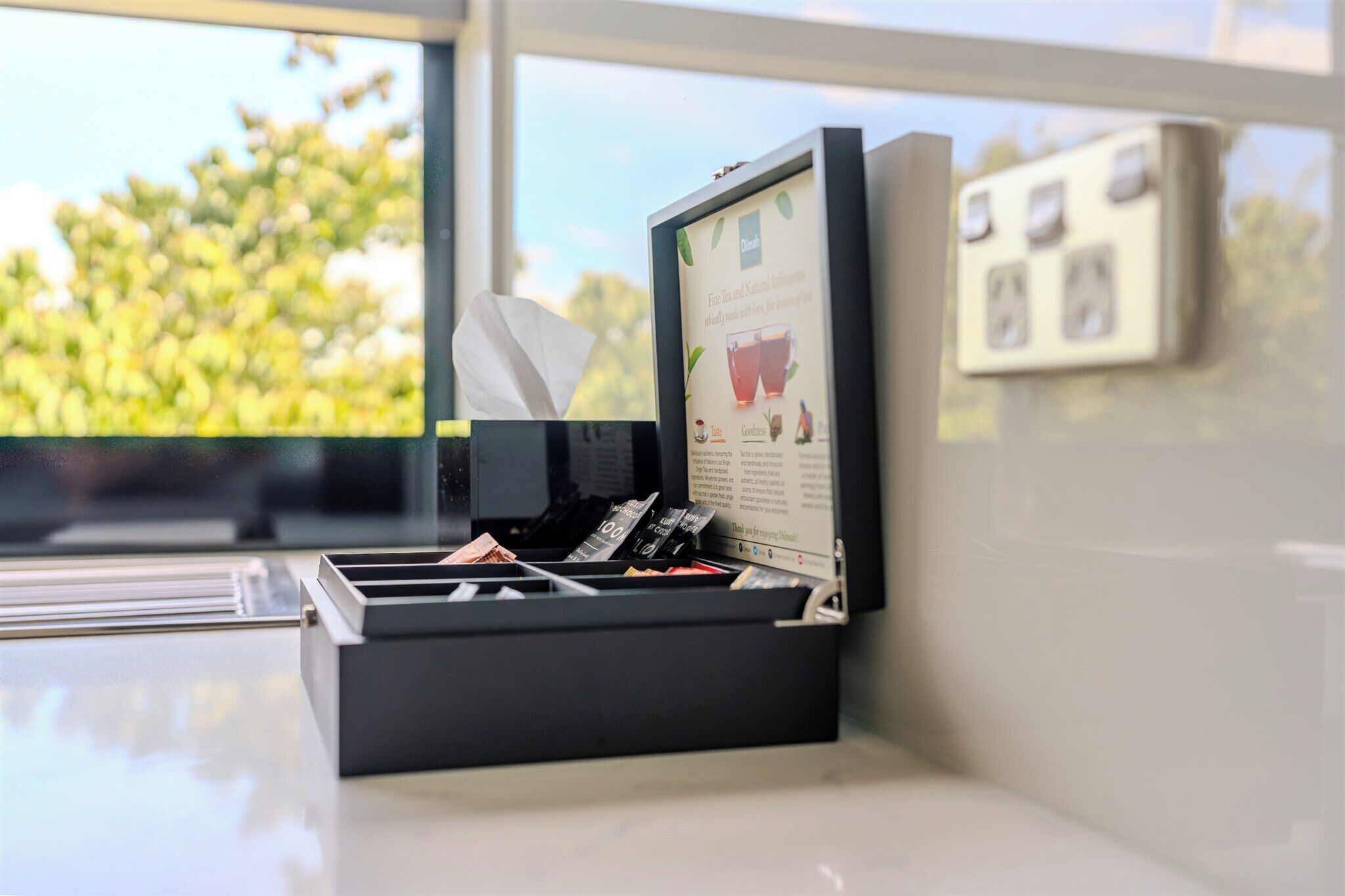 A black box with a tissue and a framed informational card on a counter by a window.