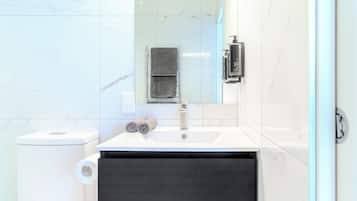 Un baño moderno con un lavamanos blanco, un espejo y un perchero para toallas.