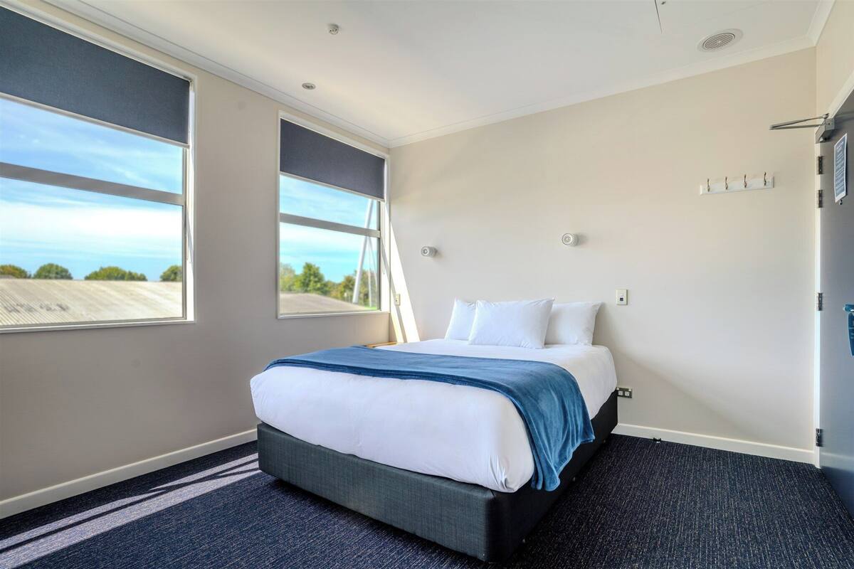 Une chambre d’hôtel avec un lit, une fenêtre et une vue sur le ciel.