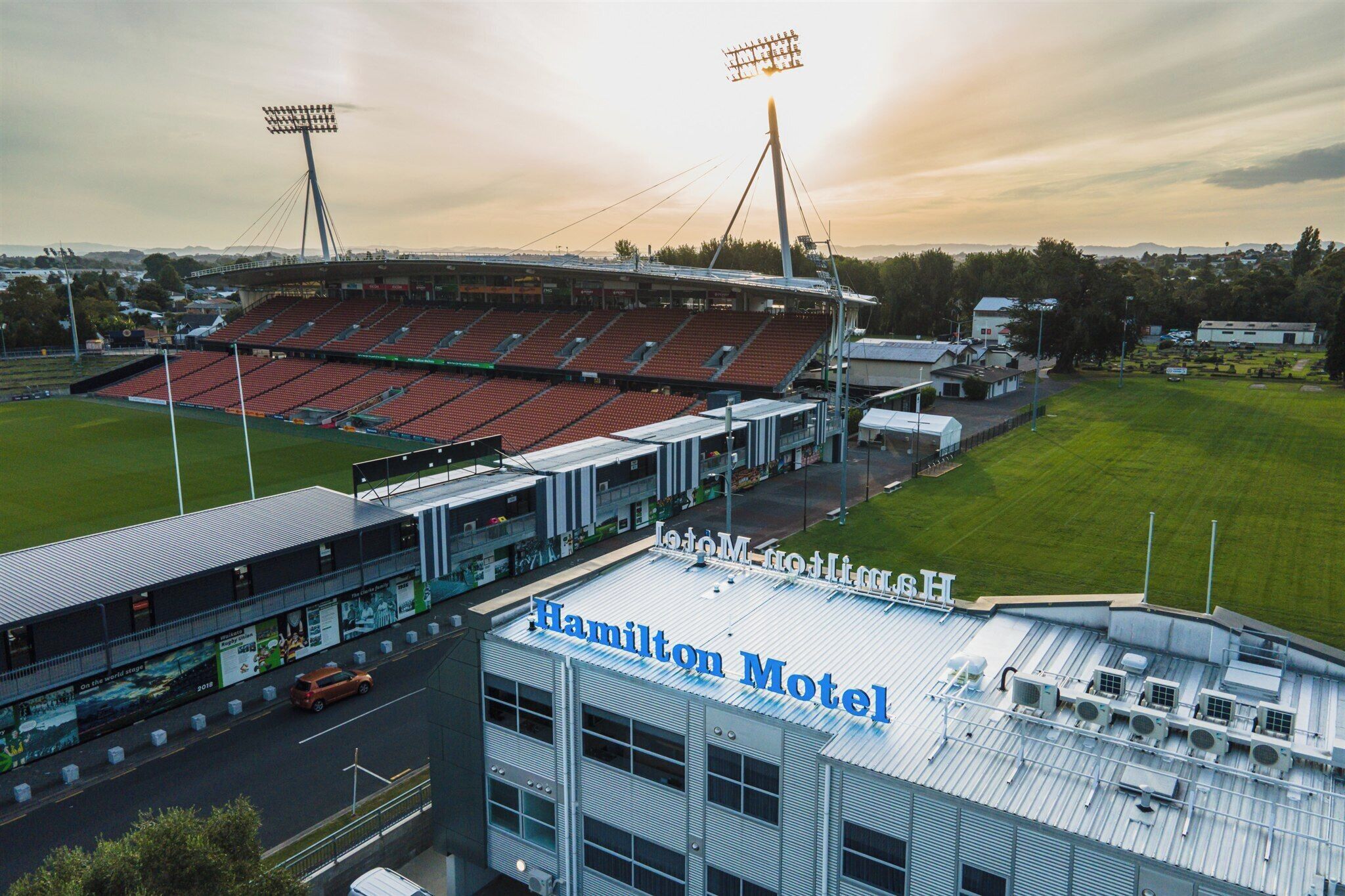 A stadium with a large seating area and a building labeled "Hamilton Motel" adjacent to it.