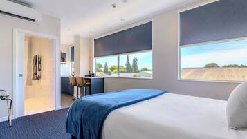 Ein Hotelzimmer mit einem großen Bett, einem Schreibtisch und Blick ins Freie.