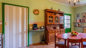 A kitchen with a dining table, chairs, a coffee maker, and a cabinet with glass doors. - Apartment Angela by Interhome (Dongo)