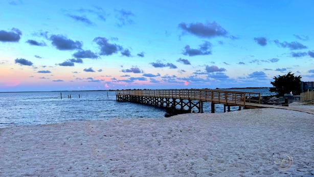 A wooden pier extending into calm waters, a sandy beach, and a clear sky with clouds. - No Cleaning Fee! Brand New Double Queen Studio Condo w/ Waterfront Pool + Beach (Southport)
