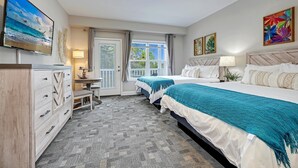 A hotel room with two beds, a TV, a desk, and a window with curtains. - No Cleaning Fee! Brand New Double Queen Studio Condo w/ Waterfront Pool + Beach (Southport)