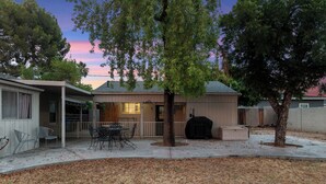 A backyard with a covered patio, a barbecue grill, and a dining area with outdoor furniture. - Sunlit Palm Cottage in Uptown Phoenix (Phoenix)