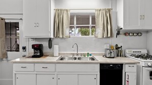 A kitchen with white cabinets, a double sink, a gas stove, and a coffee maker. - Sunlit Palm Cottage in Uptown Phoenix (Phoenix)