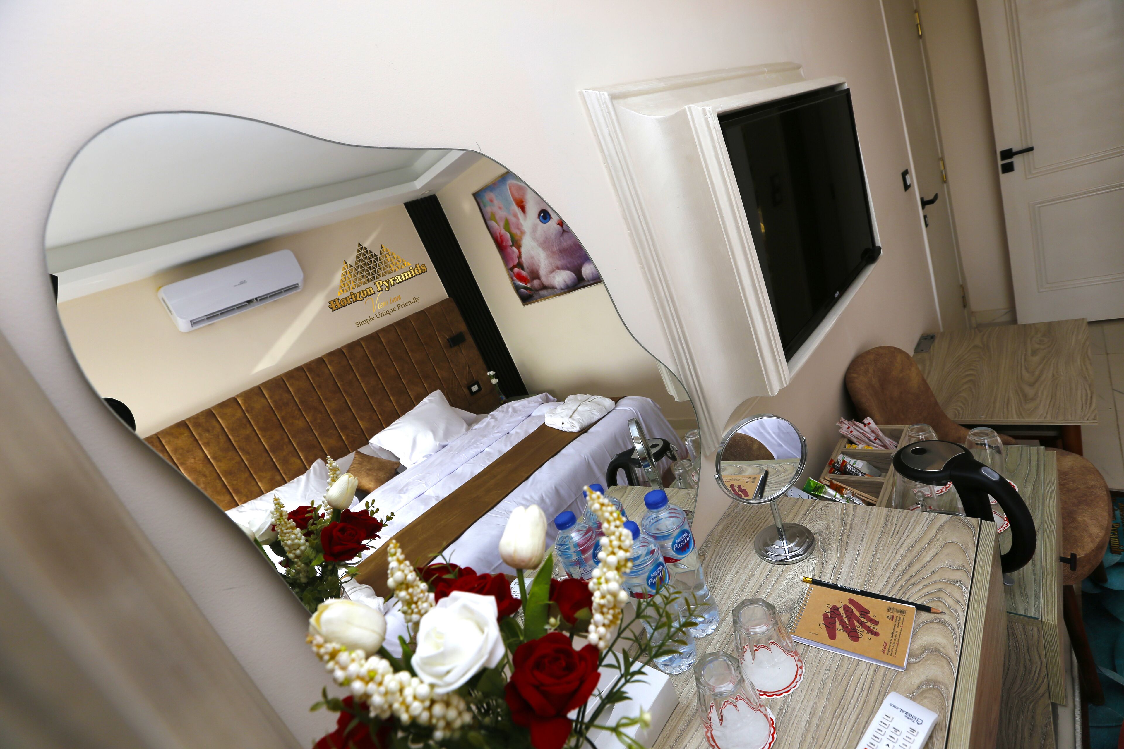 Une chambre d’hôtel avec un lit, un bureau équipé d’un ordinateur, une télévision et un miroir.