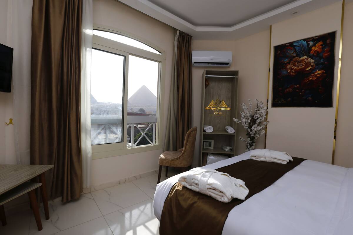 A hotel room with a bed, a desk, a chair, a wardrobe, and a painting.
