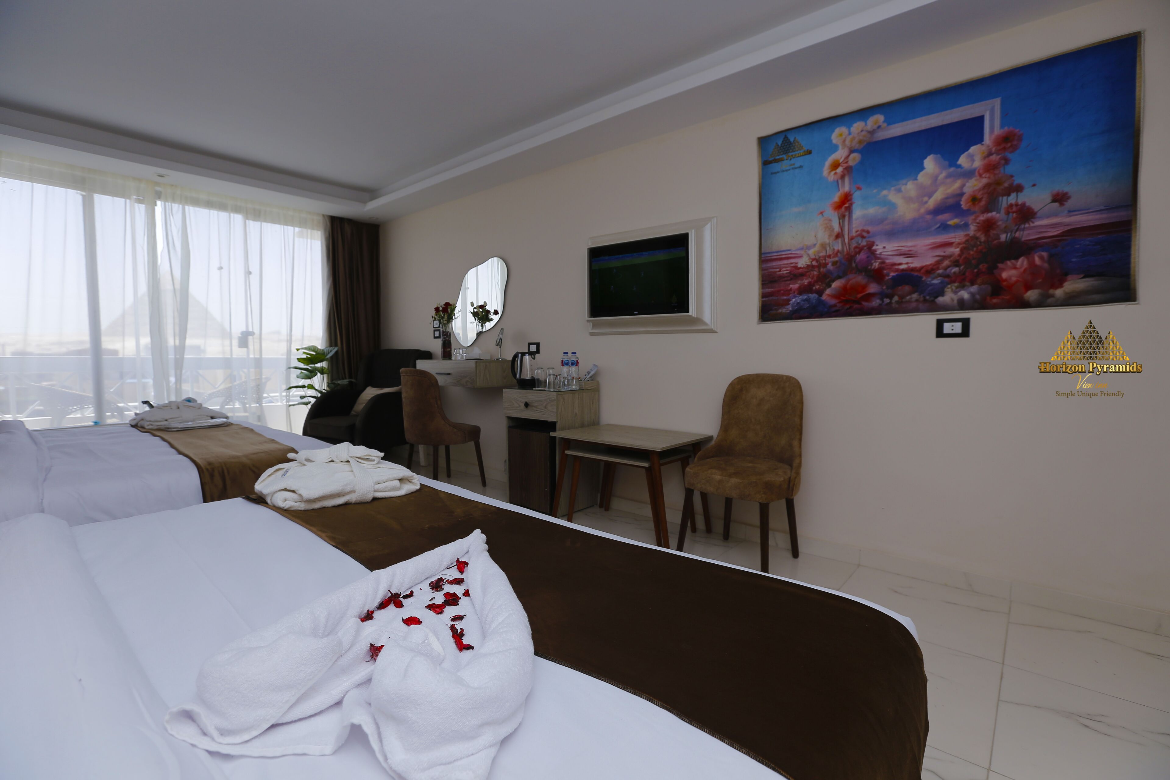 A hotel room with a bed, a desk, a chair, a TV, and a large painting on the wall.
