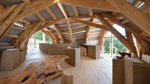 Un dormitorio estilo ático con vigas de madera a la vista, una gran mesa de madera y vistas al exterior.