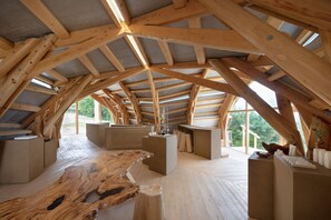 Experience the airy, open feel of this spacious attic room, featuring a large wooden table and minimalist storage units.