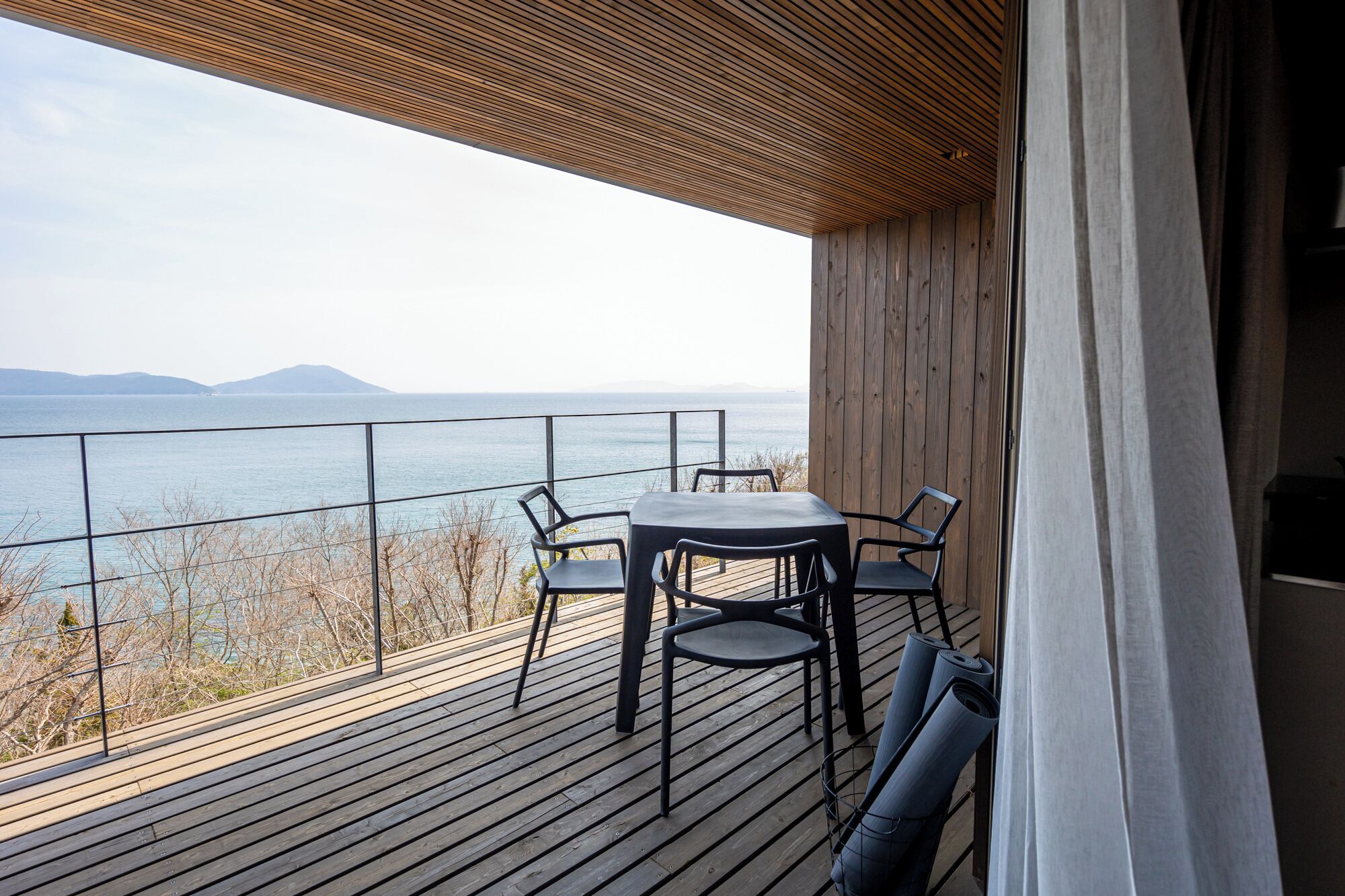 Um deck de madeira com mesa e cadeiras, dando vista para um corpo de água.