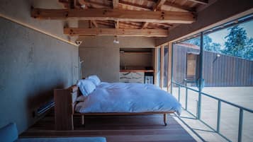 A bedroom with a wooden bed, a bench, and a large window.