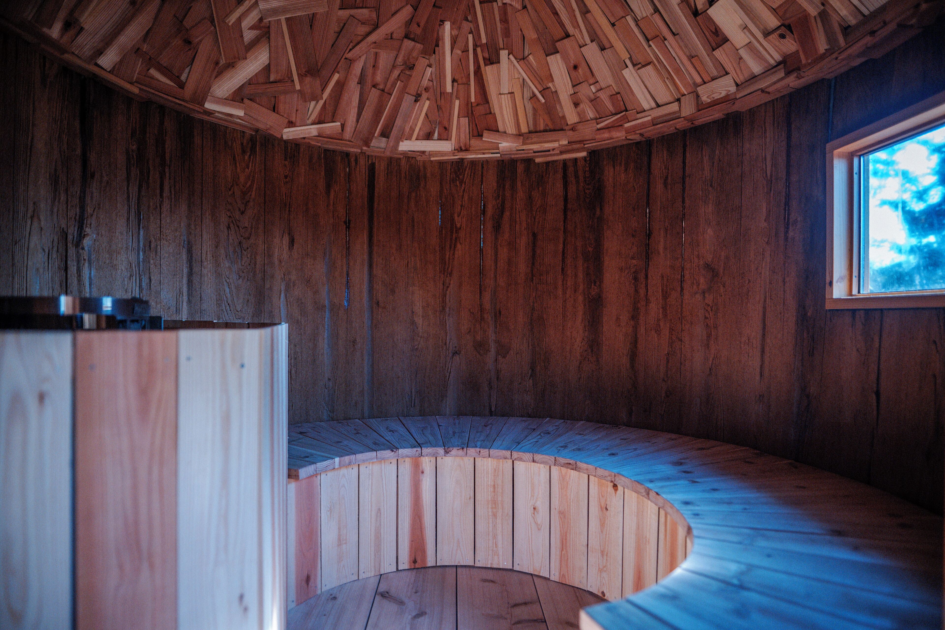 A wooden interior with a curved bench and a window.