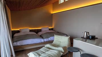 A modern bedroom with a bed, a sofa, and a small kitchenette.