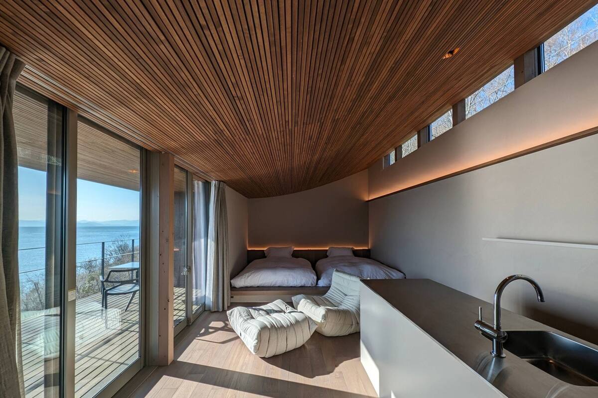 Quarto moderno com uma grande janela, teto de madeira e pia embutida.