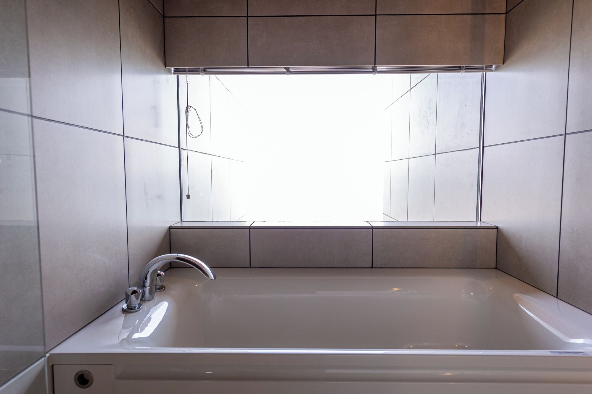 Uma casa de banho moderna com uma banheira grande, um chuveiro visível e uma janela que proporciona luz natural.