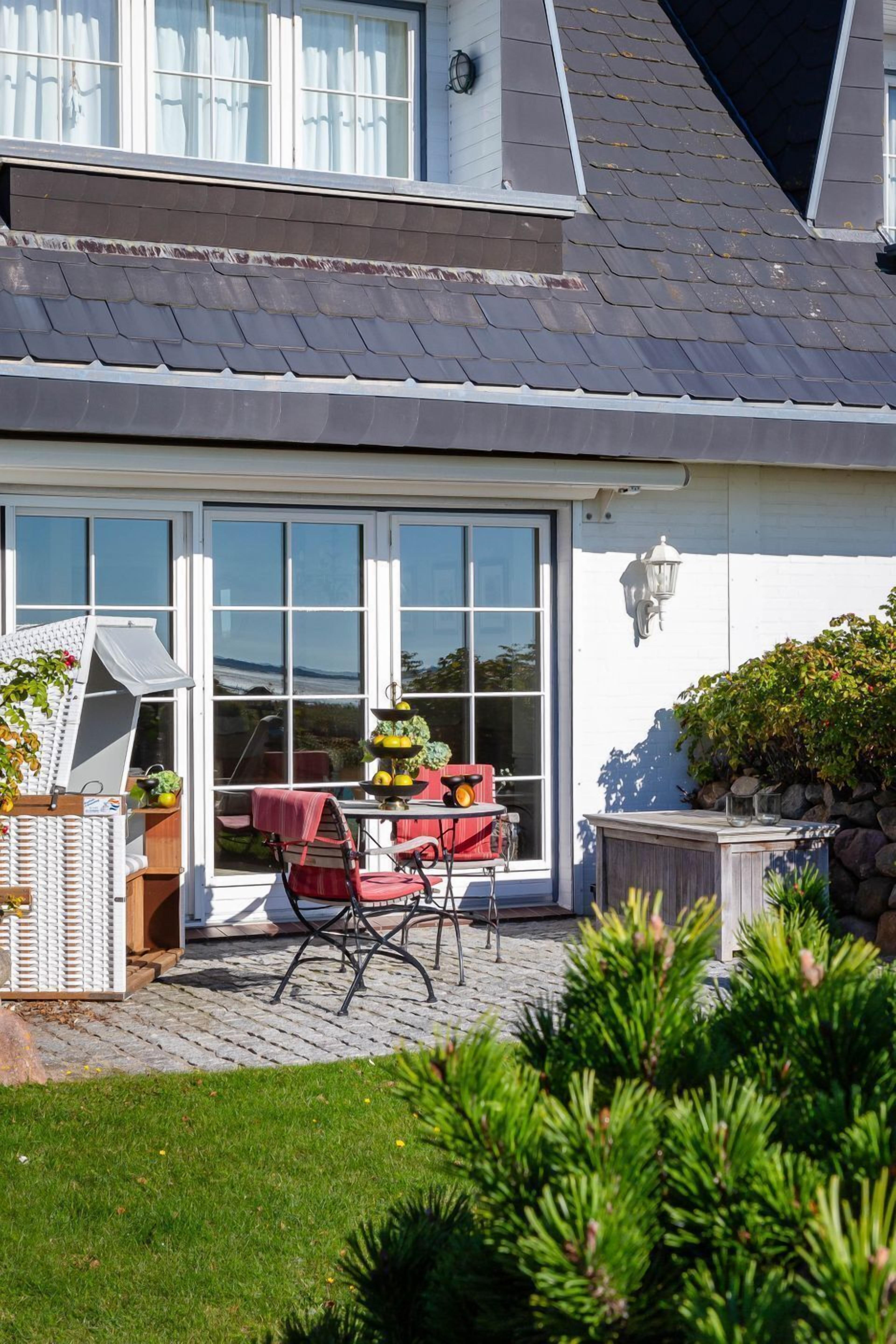 Une maison dotée d’un patio couvert, d’une table à manger avec des chaises et d’un petit jardin.