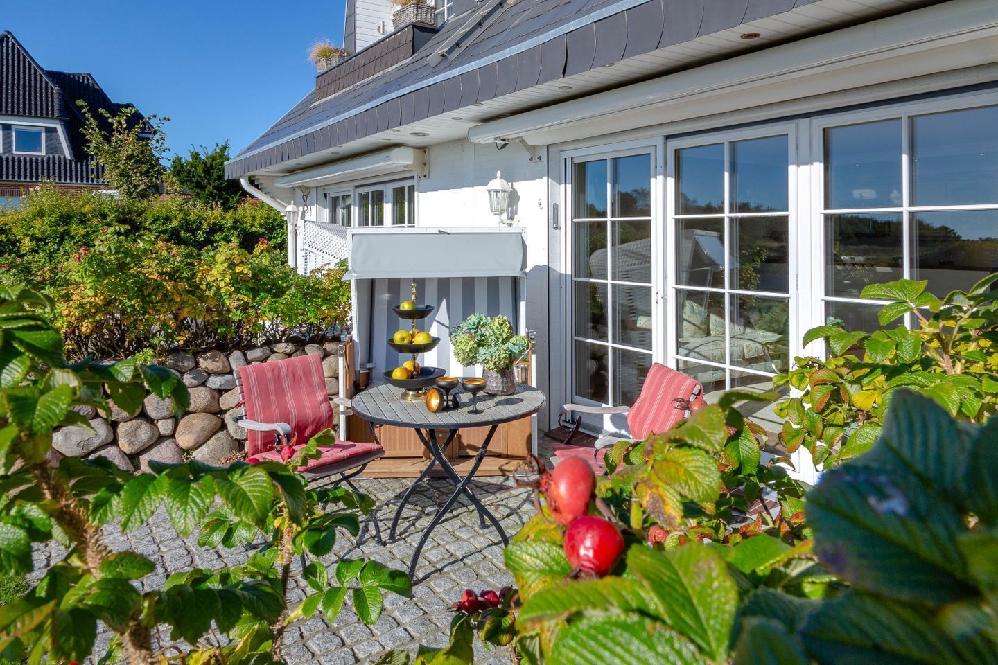Eine Terrassenfläche mit Tisch, Stühlen und einem dekorativen Obststand.