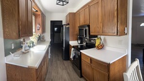 A kitchen with wooden cabinets, a black refrigerator, a microwave, and a stove. - THE SPOT, EAST SHORE (Westwood)
