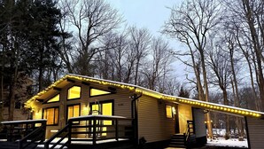 A cabin with a covered porch, a staircase, and a snow-covered ground. - Fully new 3BR House in heart of Pocono Mountains, Fire Pit! Close to Water Park! (Tobyhanna)