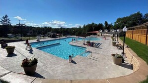 A swimming pool with a tiled deck, surrounded by potted plants and a wooden fence. - Fully new 3BR House in heart of Pocono Mountains, Fire Pit! Close to Water Park! (Tobyhanna)